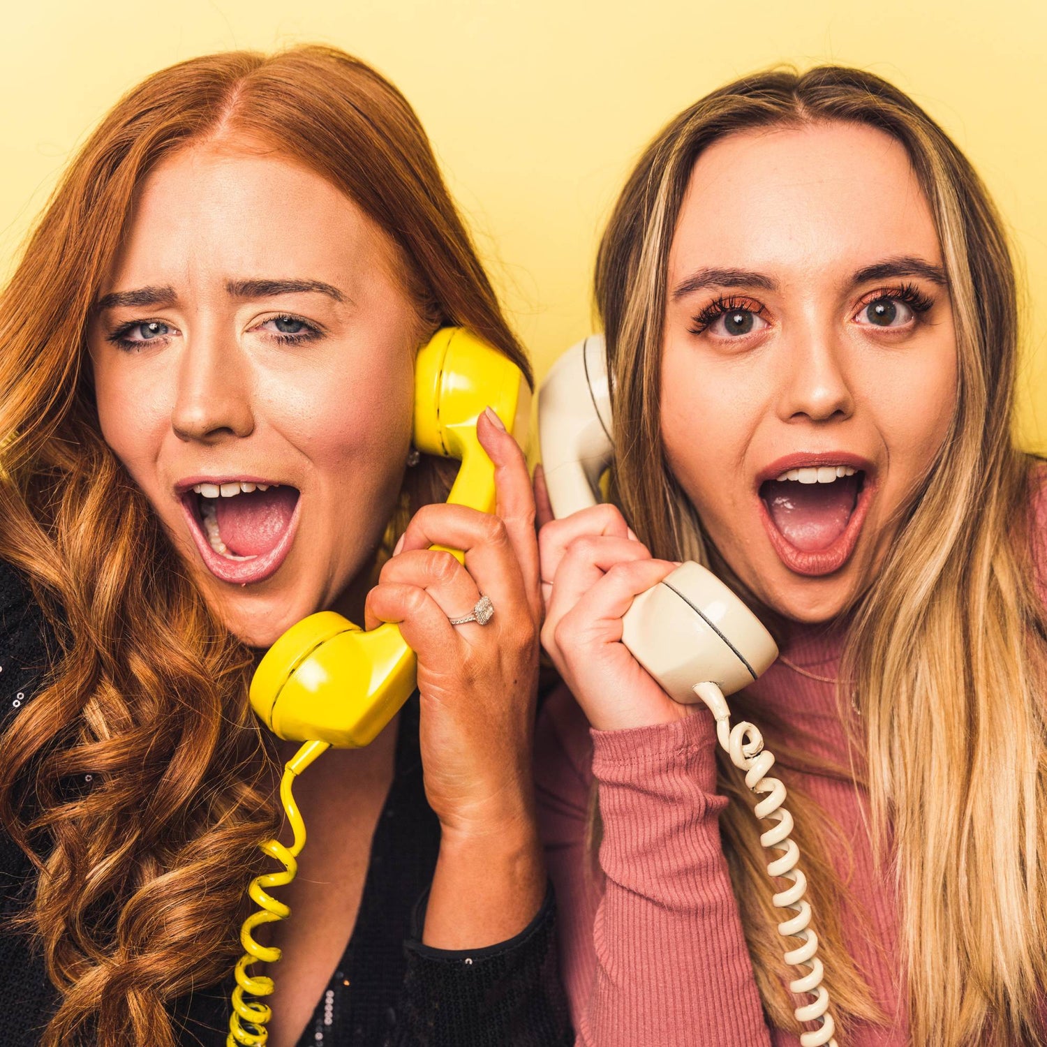two woman holding the phones